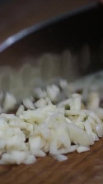 Yong Man 'in aşçısının önü ince sarımsak dilimlerini kesme tahtasında bıçakla kesiyor. Doğal ışıkla yakın çekim. Yüksek kalite 4k görüntü