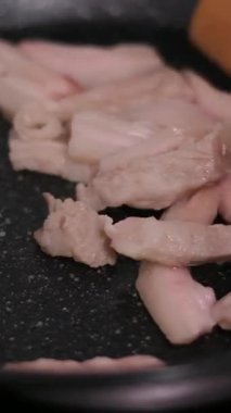 Taze bir domuz pirzolasının üzerine tuz koymak ve kızartma tavası karıştırmak. Yüksek kalite 4k görüntü