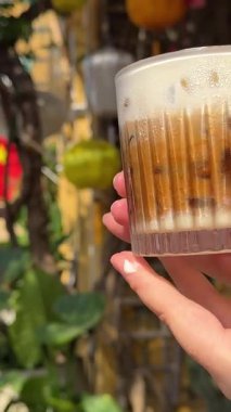 Kadın eli, arka planda bir fincan tuzlu kahve yumurtalı Vietnam kahvesi ve sokakta dolaşan bir bayrak kahvecisi tutuyor. Yüksek kalite 4k görüntü
