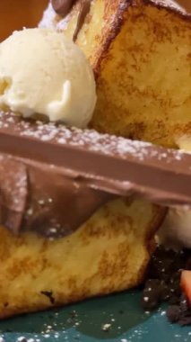 İştah açıcı Fransız tostları şık bir restoranda, mavi tabakta duruyor, tabağı çeviriyor, dondurma, çikolata, lezzetli tatlı, çilek. Yüksek kalite 4k görüntü