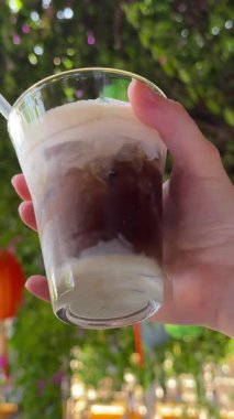 Yoğunlaştırılmış sütlü Vietnam kahvesi, elinde tuzlu kahve, sokak lambalarının üstünde, Vietnam 'da bir kalabalık arkamızda yürüyor. Yüksek kalite 4k görüntü