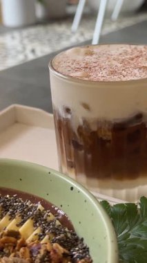 Güzel estetik kahvaltı bir kahve dükkanındaki kahverengi bir masanın üzerinde duruyor, çiçeğin yanında tuzlu kibrit kahve ve meyve suyu kasesi, meyveli yulaf ezmesi, işe yarar. Yüksek kalite 4k görüntü