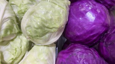 Modern bir süpermarketin sebze reyonunda plastiğe sarılı mor lahanaların yakın plan görüntüsü, taze ürünler ve sağlıklı gıda seçenekleri sergileniyor. Yüksek kalite 4k görüntü