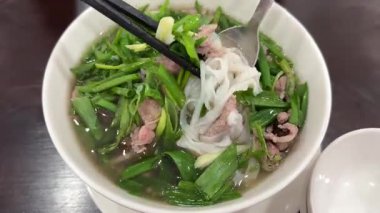 Geleneksel Vietnam et çorbası Pho 'da erişte toplamak için çubuk kullanılıyor. Vietnam usulü yemek. Et çorbası, köfte, taze sebze. Yüksek kalite 4k görüntü