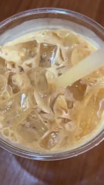 Buzlu latte kahve, ahşap masa bardağının üst görüntüsü, ferahlatıcı, kafeinli buzlar, yavaş. Yüksek kalite 4k görüntü