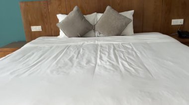 Günışığı, evdeki temiz yatak odasındaki perdelerin arasından süzülüyor. Düzgün yapılmış bir yatak ve pencerenin yanında iki sandalye. Rahatlatıcı bir atmosfer yaratıyor. Değiştirilmemiş, yavaş çekim. Yüksek kalite 4k görüntü