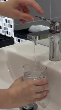 Erkek ellerinin mutfaktaki bardağa musluk suyu dökmesini kapat. Yüksek kalite 4k görüntü