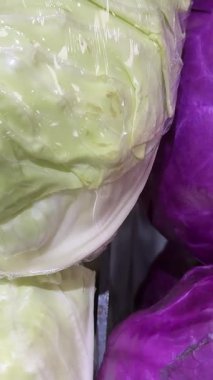 Modern bir süpermarketin sebze reyonunda plastiğe sarılı mor lahanaların yakın plan görüntüsü, taze ürünler ve sağlıklı gıda seçenekleri sergileniyor. Yüksek kalite 4k görüntü