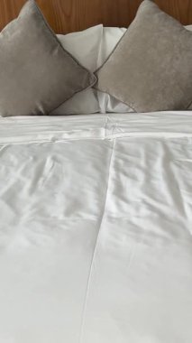 Günışığı, evdeki temiz yatak odasındaki perdelerin arasından süzülüyor. Düzgün yapılmış bir yatak ve pencerenin yanında iki sandalye. Rahatlatıcı bir atmosfer yaratıyor. Değiştirilmemiş, yavaş çekim. Yüksek kalite 4k görüntü