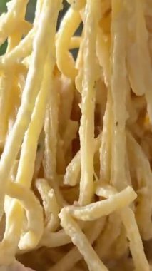 Bir çatal zarif bir şekilde kremalı carbonara tabakasında dönerken yakalanan büyüleyici bir an. Dönüşü zengin dokuları vurguluyor, izleyiciyi lezzetin tadını çıkarmaya davet eden bir görsel yaratıyor..