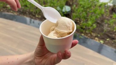 Beyaz bardakta dondurma, karamel serpiştirilmiş ve karamelli, tahta kaşıkla serpiştirilmiş. Yüksek kalite 4k görüntü