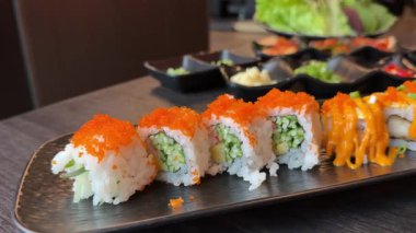 Çeşitli ekmekli suşi tabağı, balık yumurtası, susam, sos ve zencefil, ağır çekim masa çekimi. Yüksek kalite 4k görüntü