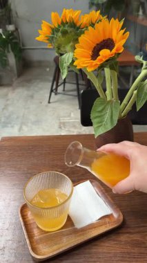 Masanın üzerinde bir bardak portakal suyu ve ayçiçeği var. Yüksek kalite 4k görüntü