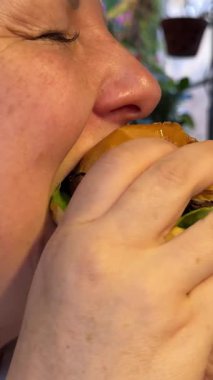 Kafkas kadın müşteri müşterisi abur cubur yiyor hamburger çiğniyor, hamburger çiğniyor, zevk alıyor beslenme düzenini aldatıyor, yemek cezbediyor. Sağlıksız abur cubur, aşırı kalori tüketimi..