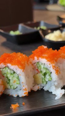 Çeşitli ekmekli suşi tabağı, balık yumurtası, susam, sos ve zencefil, ağır çekim masa çekimi. Yüksek kalite 4k görüntü