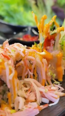 Modern bir restoranda, yanında renkli tabaklar bulunan çarpıcı bir suşi tabağının tadını çıkarın. Yüksek kalite 4k görüntü