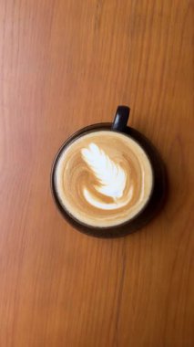 Tahta sehpanın üzerinde sıcak latte sanat kahvesi, dinlenme zamanı. Yüksek kalite 4k görüntü
