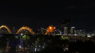 Ateşli ejderha köprüsü gece vakti Da Nang gökyüzünü aydınlatıyor, Han Nehri 'nin sularında canlı yansımalar yaratıyor, Orta Vietnam' daki mimari mucizeleri vurguluyor. Yüksek kalite 4k görüntü
