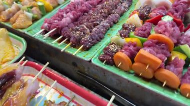 Sokak yemekleri şefi Gece Pazarı 'nda et, sebze ve ananas şişleri pişiriyor ve canlı Tayland gece yemeği kültürünü yakalıyor. Yerel yemek. Yüksek kalite 4k görüntü