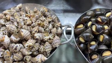 Limon ve yemek çubuklarıyla servis edildiğinde otantik geleneksel tencerede lezzetli bir şekilde pişirilmiş salyangoz. Deniz ürünleri aşıkları için tecrübe. Yüksek kalite 4k görüntü