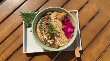 Sağlıklı tropik meyve suyu kutusu ahşap bir masada duruyor. Kahvaltı muz, müsli, meyve ve yeşillik, omlet ve kibrit çiçekleriyle dengelenir. Yüksek kalite 4k görüntü