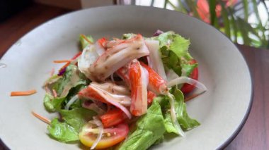 Gastronomi. Sağlıklı gıda ve beslenme. Mısır taneleri, marul, salatalık, siyah zeytin ve yengeç çubuklarıyla taze bir salata tabağı hazırlıyorum. Yüksek kalite 4k görüntü