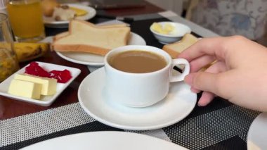 Restoranda kahvaltı. Taze hamur işleri, meyveler, omlet, tost, yoğurt ve ahşap masada bir fincan kahve. Otelde günaydın. Yüksek kalite 4k görüntü