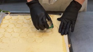 Pastanelerde tatlı yapma süreci hamur işi eldivenlerle çalışma kalıplardan daireler kesme pasta pişirme aşçısı tatlıları pişirme.