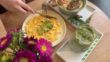 Şirin bir kahve dükkanında estetik kahvaltı yumurtalı smoothie bowl yulaf ezmesi güzel pembe çiçekler sağlıklı yemek brunch 'ıyla çıkıyor. Yüksek kalite 4k görüntü