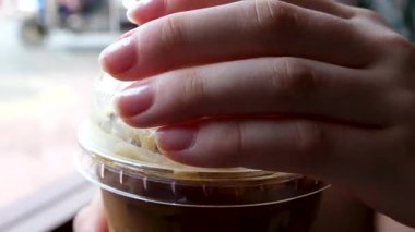 Pipetle karıştırılan buzlu kahvenin yakın çekim videosu, dönen buz küpleri, ardından da plastik kapağın kapatılması. Rahatlatıcı ve tatmin edici bir içki hazırlama sahnesi. Yüksek kalite 4k görüntü