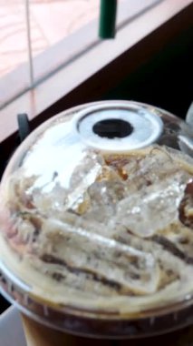 Pipetle karıştırılan buzlu kahvenin yakın çekim videosu, dönen buz küpleri, ardından da plastik kapağın kapatılması. Rahatlatıcı ve tatmin edici bir içki hazırlama sahnesi. Yüksek kalite 4k görüntü