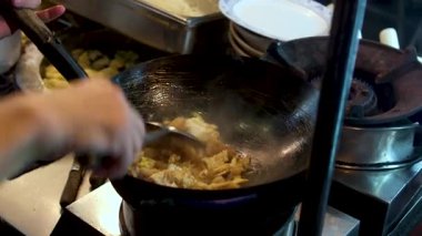 Ticari bir mutfaktaki dökme demir bir tavada sığır eti ve sarımsakla kızartılmış sebze kızartmak, flambe tarzı pişirmek. Kapatın. Yüksek kalite 4k görüntü