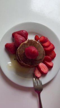 Maple syrup poured onto American pancakes with strawberries. homemade pancakes with syrup and strawberries for morning breakfast. breakfast recipe. High quality 4k footage