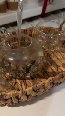 Sinema - yavaş çekimde cam çaydanlıktan sıcak çayı bitkiler ve limonla bardağa dökerken. Sıcak ve rahat bir ortam. Yüksek kalite 4k görüntü