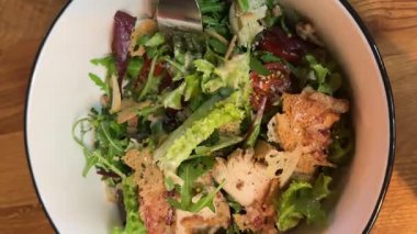 İçinde tavuk, parmesan peyniri, domates, kızarmış ekmek, marul yaprağı, keten tohumu, ayçiçeği ve susam tohumu olan bir kâse dolusu sezar salatası. Yüksek kalite 4k görüntü