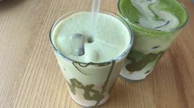 Yaz ferahlatıcı içecek buzlu matcha latte hazırlığı, taze kremalı sütlü, sinematik yakın çekim içine kibrit yeşil çay karışımı dökmek. Yüksek kalite 4k görüntü