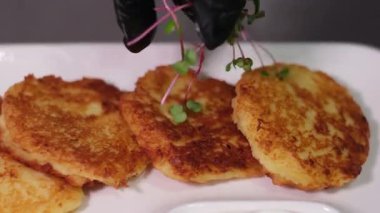 Ekşi kremalı ve siyah tabakta salatalıklı patates gözlemesi. Yüksek kalite 4k görüntü