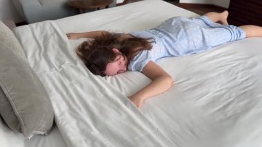 Tom Lada kızı beyaz bir yatakta uzanıyor ve kollarını sallayarak uyuyor. Kahverengi saçlı ergen bunalımı geçiriyor. Yüksek kalite 4k görüntü