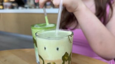 Bardakta fıstık ezmesi. Süt köpüğünde dahice bir deseni olan güzel bir fincan mat yeşil çay. Bardak ahşap bir tepside duruyor. Masayla aynı renk düzeninde.. 