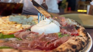 Erkek ellerinin lezzetli pizzanın üzerine sos sosu dökerken yakın plan. Taze domates, jambon, salata ve burrata peyniri. Aşçılığın sonuna acı tat için bazı malzemeler ekliyor. burrata