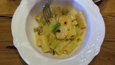 Pişmiş kelebek şekilli makarna servis ediyoruz. Kaynamış karides kuyruklu farfalle deniyor. Masada kareli masa örtüsüyle kaplı bir tabakta. Yüksek kalite 4k