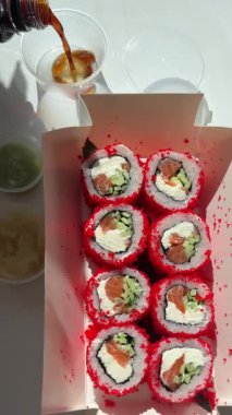 Soya sosuna batırılmış suşi rulosu. Siyah arka plan dikey video. Adam sosa batırıp, çubuklarla suşi yiyor. Yüksek kalite 4k görüntü