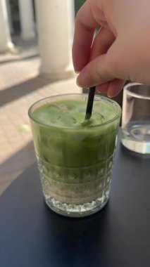 Yaz ferahlatıcı içecek buzlu matcha latte hazırlığı, taze kremalı sütlü, sinematik yakın çekim içine kibrit yeşil çay karışımı dökmek. Yüksek kalite 4k görüntü