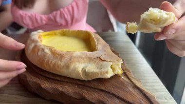 Kadınların elleri Adjarian Khachapuri 'den bir parça koparıp erimiş peynir ve yumurta sarısı karışımına batırıyor. Geleneksel Gürcü yemek kavramının tadını çıkarıyorum. khachapuri