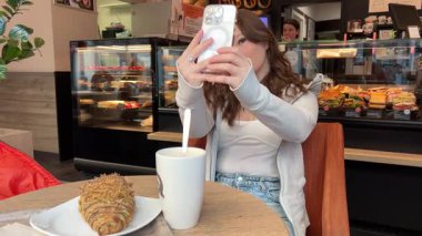 Sevimli güzel bir kadın Avrupa 'nın bir şehrinde balkonda selfie çekiyor. Balkonda kahvaltı var. Şehirde uyanmak gibi. Avrupa yaşam tarzı. Sabah rutini. Yüksek kalite 4k görüntü