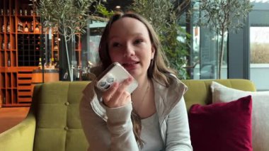 Mutlu, mutlu, mutlu, kaygısız, neşeli, beyaz kadın, kanepede oturmuş, cep telefonu akıllı telefonuyla kayıyor, rahatlıyor, sohbet ediyor, sosyal medya uygulaması bağımlısı.