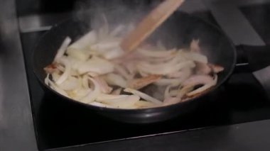 Silikon spatulayla soğan karıştırmak. Tahta kesme tahtasından doğranmış soğanları sıcak tavaya atmak. Yüksek kalite 4k görüntü