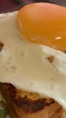 Nefis bir kahvaltı. Yumurta ve salatalı tost. İçinde hazır kare tost ve sahanda yumurta olan bir tabak servis ediyorum. Yakın plan, ön görüş, arka plan. Yüksek kalite 4k görüntü