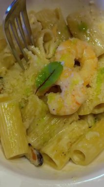 Pişmiş kelebek şekilli makarna servis ediyoruz. Kaynamış karides kuyruklu farfalle deniyor. Masada kareli masa örtüsüyle kaplı bir tabakta. Yüksek kalite 4k