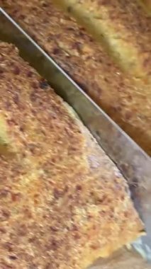 Kadın şefin somun ekmeği tahta tahtada bıçakla kesmesine, doğal ışık altında eşit parçalara ayırmasına, bıçağın kabuktan geçmesine ve düzgün dilimler oluşturmasına odaklan. Yüksek